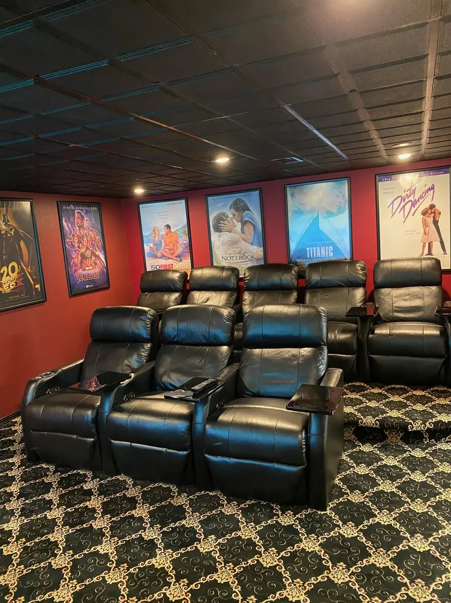 Two rows of black leather theater recliners with framed movie posters